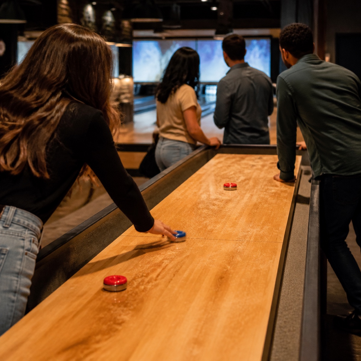 Friends playing shuffleboard at an indoor games venue